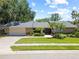Charming single-story home features a manicured lawn and lush landscaping at 1810 Pine Hill Dr, Safety Harbor, FL 34695