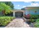 Inviting front entrance with lush landscaping, brick walkway, and a screened front door at 1810 Pine Hill Dr, Safety Harbor, FL 34695