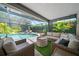 Screened-in outdoor living area with a cozy seating area near lush landscaping and pool at 1810 Pine Hill Dr, Safety Harbor, FL 34695