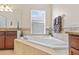 Relaxing bathtub area with tiled surround, a window for natural light, and dark wood cabinets at 19309 Prairie Tree Pl, Tampa, FL 33647