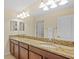 Bathroom featuring a double vanity with granite countertops and a well-lit mirror at 19309 Prairie Tree Pl, Tampa, FL 33647
