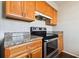 Kitchen features wood cabinets, granite countertops, and stainless steel oven/stove with range hood at 200 Country Club Dr # 308, Largo, FL 33771