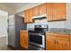 Modern kitchen with stainless steel appliances, granite countertops, wooden cabinets, and dark wood-look flooring at 200 Country Club Dr # 308, Largo, FL 33771
