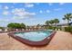 View of a pool with lounge chairs, palm trees and nearby apartment buildings under a blue sky at 200 Country Club Dr # 308, Largo, FL 33771