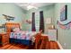 Cozy bedroom with hardwood floors, ceiling fan, airplane decor, and one window with dark curtains at 22304 Stillwood Dr, Land O Lakes, FL 34639