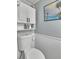Clean toilet with mounted cabinet and beach-themed artwork at 2331 Belleair Rd # 214, Clearwater, FL 33764