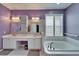 Bright bathroom featuring a double vanity, soaking tub with shuttered window, and mosaic tile accents at 2510 Cross More St, Valrico, FL 33594