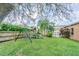 Large grassy backyard featuring playset, mature landscaping, and privacy fence at 2706 Bent Leaf Dr, Valrico, FL 33594