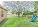 Spacious backyard with lush green lawn, mature trees, and a fun swing set for play at 2706 Bent Leaf Dr, Valrico, FL 33594