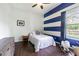 Cozy bedroom featuring wood-look floors, blue-and-white striped accent wall, and a bright window at 2706 Bent Leaf Dr, Valrico, FL 33594