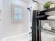 Elegant bathroom with tiled shower/tub combo, black hardware, and a functional shelving unit for storage and organization at 2874 Bayshore Trails Dr, Tampa, FL 33611