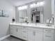 Ensuite bathroom features a double sink vanity with white cabinets, quartz countertops, and decorative mirrors at 2874 Bayshore Trails Dr, Tampa, FL 33611