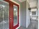 Charming red front door with glass panels, leading to a covered porch with outdoor seating at 2874 Bayshore Trails Dr, Tampa, FL 33611