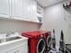 Bright laundry room featuring a modern, red washer and dryer, a utility sink, and ample storage at 2874 Bayshore Trails Dr, Tampa, FL 33611