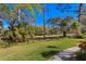 Beautifully landscaped backyard featuring green grass, mature trees, and a walking path at 3109 Tarpon Woods Blvd, Palm Harbor, FL 34685