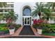 Elegant building entrance featuring a grand archway, manicured landscaping, and vibrant red flower bushes at 4750 Dolphin Cay S Ln # 209, St Petersburg, FL 33711