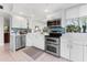 Modern kitchen with white cabinets, stainless steel appliances, and blue backsplash tiles at 4750 Dolphin Cay S Ln # 209, St Petersburg, FL 33711