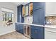 Stylish bar area with custom blue cabinets, wine rack, and marble backsplash at 5809 Alabaster Stone Ln, Apollo Beach, FL 33572