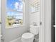 Bright bathroom with a toilet next to a window, offering a view of neighborhood homes at 5809 Alabaster Stone Ln, Apollo Beach, FL 33572