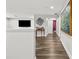 Bright, modern hallway with hardwood floors, TV, and recessed lighting at 5809 Alabaster Stone Ln, Apollo Beach, FL 33572