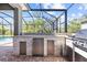 Outdoor kitchen with stone facade, stainless steel appliances, and a view of the pool at 5809 Alabaster Stone Ln, Apollo Beach, FL 33572
