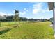 Expansive backyard featuring well-kept lawn, bordered by a black iron fence and mature trees in the distance at 6426 Bradford Woods Dr, Zephyrhills, FL 33542