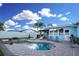 This backyard oasis features a relaxing pool with waterfall features, lounge chairs, and palm trees at 6513 14Th W Ave, Bradenton, FL 34209