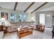 Cozy living room featuring vaulted ceilings, exposed beams, and neutral-toned tile floors at 6513 14Th W Ave, Bradenton, FL 34209