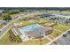 Overhead view of community amenities including a large pool, clubhouse, playground, tennis courts, and manicured lawns at 6748 Ripple Pond Loop, Zephyrhills, FL 33541