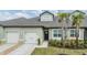 Charming townhome with a light green exterior, complemented by a well-manicured lawn and a convenient two-car garage at 6748 Ripple Pond Loop, Zephyrhills, FL 33541