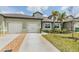 Inviting townhome featuring a well-kept lawn, a two-car garage, and lush landscaping, creating a warm and welcoming ambiance at 6748 Ripple Pond Loop, Zephyrhills, FL 33541