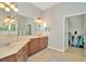 Bathroom featuring a double sink vanity, a large mirror, vanity lighting and a doorway to a walk-in closet at 7051 Derwent Glen Cir, Land O Lakes, FL 34637