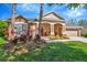 Charming home featuring a stone and stucco facade, arched entryway, and well-manicured landscaping at 7051 Derwent Glen Cir, Land O Lakes, FL 34637