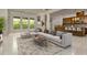 Expansive living room features large windows, a comfortable sectional sofa, and seamless flow to the kitchen at 7051 Derwent Glen Cir, Land O Lakes, FL 34637