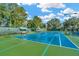 Well-maintained tennis court with green and blue surfaces surrounded by trees under a clear sky at 7051 Derwent Glen Cir, Land O Lakes, FL 34637