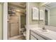Well-lit bathroom with tiled shower, vanity, and shuttered medicine cabinet at 7509 Rocky Point Dr, Hudson, FL 34667