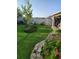 Landscaped backyard with a well-maintained lawn, stone pathway, and a variety of flowering plants and trees at 7737 Sail Clover Ln, Zephyrhills, FL 33540