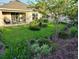 Expansive backyard featuring lush landscaping, including trees, shrubs, and a patio seating area for outdoor entertaining at 7737 Sail Clover Ln, Zephyrhills, FL 33540