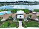 Aerial view of the clubhouse with a swimming pool, lake view, covered seating area, and palm trees at 7737 Sail Clover Ln, Zephyrhills, FL 33540