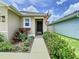 Inviting front entrance with a charming wreath, beautiful landscaping and a concrete pathway at 7737 Sail Clover Ln, Zephyrhills, FL 33540
