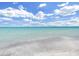 Scenic beach view with gentle waves meeting soft sands beneath a bright blue sky with fluffy white clouds at 101 Gulf Blvd, Belleair Beach, FL 33786