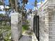 Open gate leading to a beach property with white brick pillars and lush surroundings at 101 Gulf Blvd, Belleair Beach, FL 33786