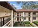 Condo exterior with red tile roof, upper and lower door wreaths, black railings, and mature landscaping at 110 Hammock Pine Blvd # 110, Clearwater, FL 33761