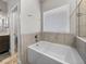 Bathroom with a soaking tub, tiled walls, and a window with privacy blinds at 11465 June Briar Loop, San Antonio, FL 33576