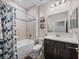 Bathroom with a shower over tub with a patterned shower curtain and a dark wood single sink vanity at 11465 June Briar Loop, San Antonio, FL 33576