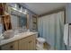 Bathroom with a large framed mirror, marble counters, and a shower behind a patterned shower curtain at 11590 Shipwatch Dr # 342, Largo, FL 33774