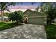 Charming home showcasing an attached garage, well-kept lawn, and a vibrant orange front door at sunset at 1187 Mistwood Dr, Tarpon Springs, FL 34688