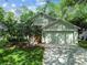 Well-kept house featuring a two-car garage, with a bright red door and lush landscaping at 1187 Mistwood Dr, Tarpon Springs, FL 34688