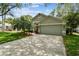 Charming home showcasing an attached garage, well-kept lawn, and a vibrant orange front door at 1187 Mistwood Dr, Tarpon Springs, FL 34688