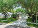 A single-Gathering home featuring mature shade trees, lush grass and an elongated driveway at 1187 Mistwood Dr, Tarpon Springs, FL 34688